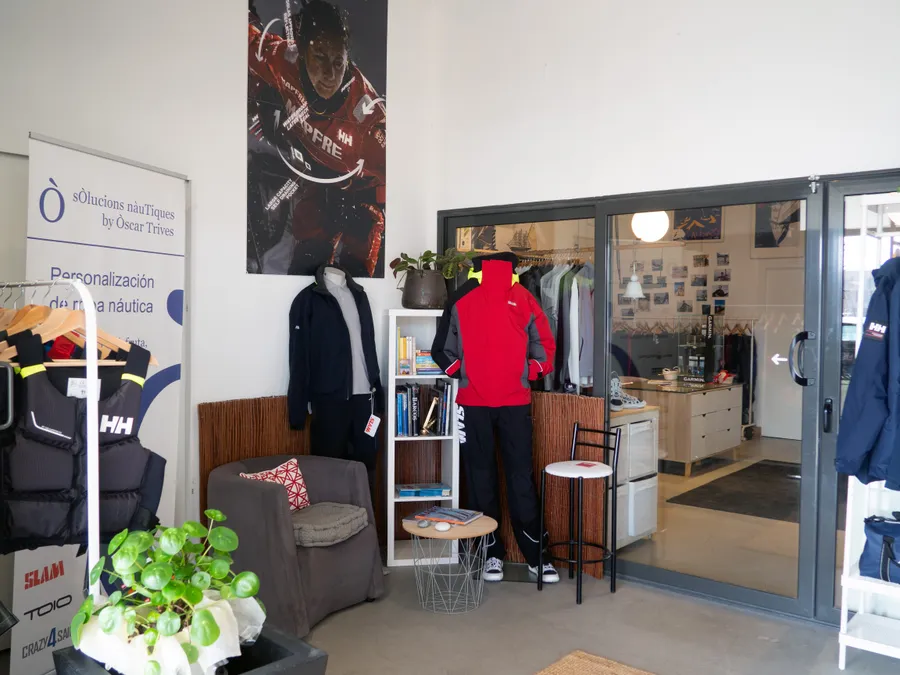 Interior del showroom del Port Marina Vela, amb rails de roba tècnica, armilles i maniquins.