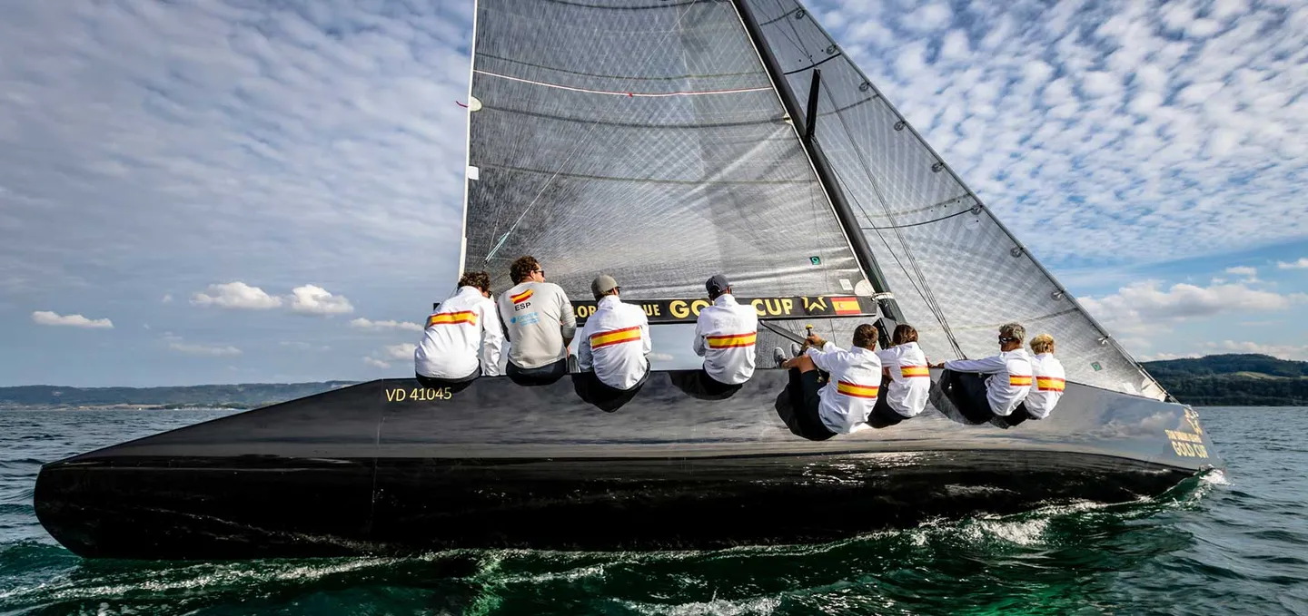 Tripulació asseguda a la banda d'un veler de regata, tota amb la mateixa equipació.